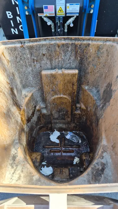 Interior of a heavily soiled brown trash bin before cleaning